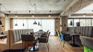A modern restaurant with booth seating, wooden floors, and pendant lighting. - Loom Hotel (Bolzano)