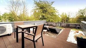 A rooftop patio with a wooden table and chairs, a grill, and a seating area with cushions. - LA GRANGE AU CORPS (Gussignies)