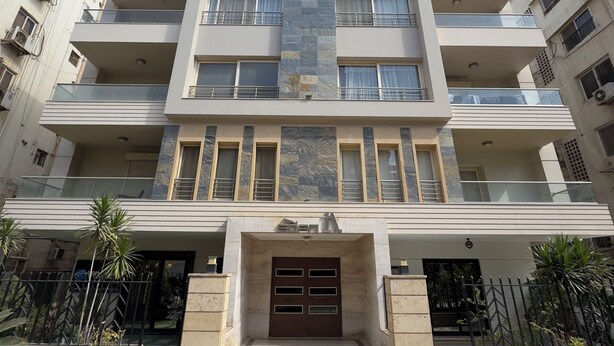 Un immeuble résidentiel à plusieurs étages, doté d’une entrée centrale, de balcons et d’une façade en pierre.