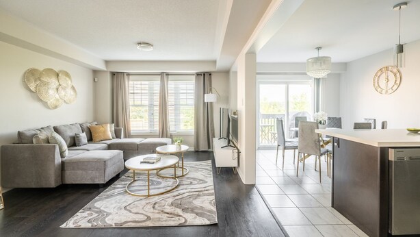 A modern living room with a grey sofa, a coffee table, and a dining area with a kitchen island. - GLOBALSTAY. Modern 3 Bedroom House in Brampton. BBQ, parking. (Brampton/Canada)