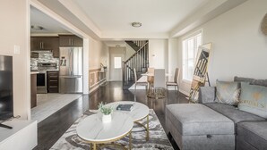 A modern living room with a grey sofa, a white coffee table, and a dining area with a round table and chairs. - GLOBALSTAY. Modern 3 Bedroom House in Brampton. BBQ, parking. (Brampton/Canada)