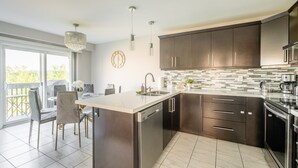 A modern kitchen with dark cabinetry, a large island, and a dining area with a view. - GLOBALSTAY. Modern 3 Bedroom House in Brampton. BBQ, parking. (Brampton/Canada)
