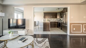 A modern living room with a flat-screen TV, a marble coffee table, and a dining area with chairs. - GLOBALSTAY. Modern 3 Bedroom House in Brampton. BBQ, parking. (Brampton/Canada)