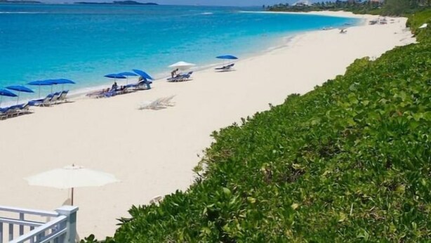 A beach with white sand, clear blue water, and a few umbrellas. - Seaclusion - Private Pool near Atlantis+Beach (Paradise Island)