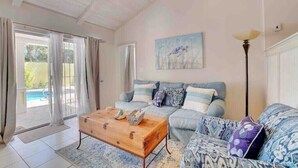A living room with a sofa, a coffee table, and a painting on the wall. - Seaclusion - Private Pool near Atlantis+Beach (Paradise Island)