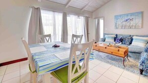 A dining area with a table set for two, a wooden coffee table, and a sofa in the background. - Seaclusion - Private Pool near Atlantis+Beach (Paradise Island)