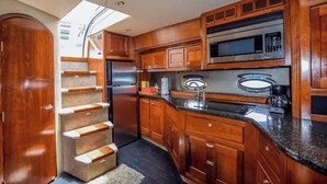 A compact kitchen with wooden cabinets, a microwave, and a stainless steel refrigerator. - Luxury Yacht  Steps from Atlantis & Restaurants! (Paradise Island)