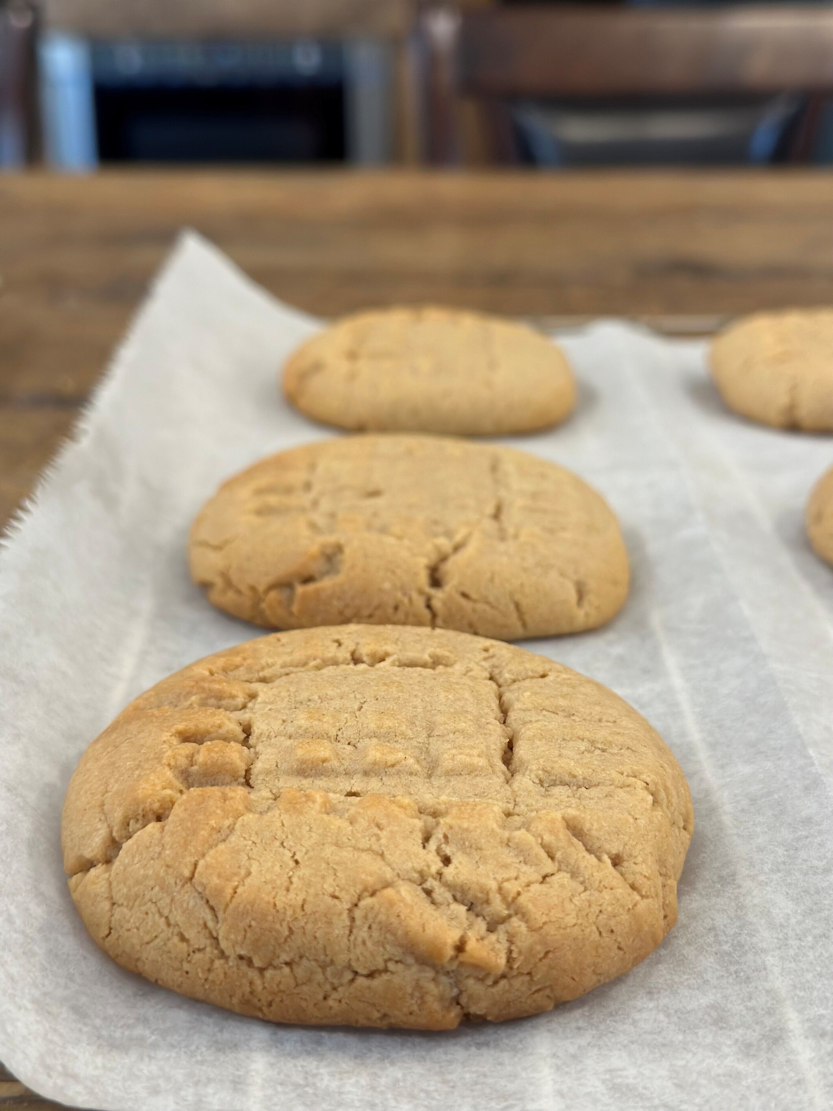 A table with three cookies on parchment paper.