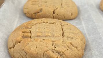 A table with three cookies on parchment paper.