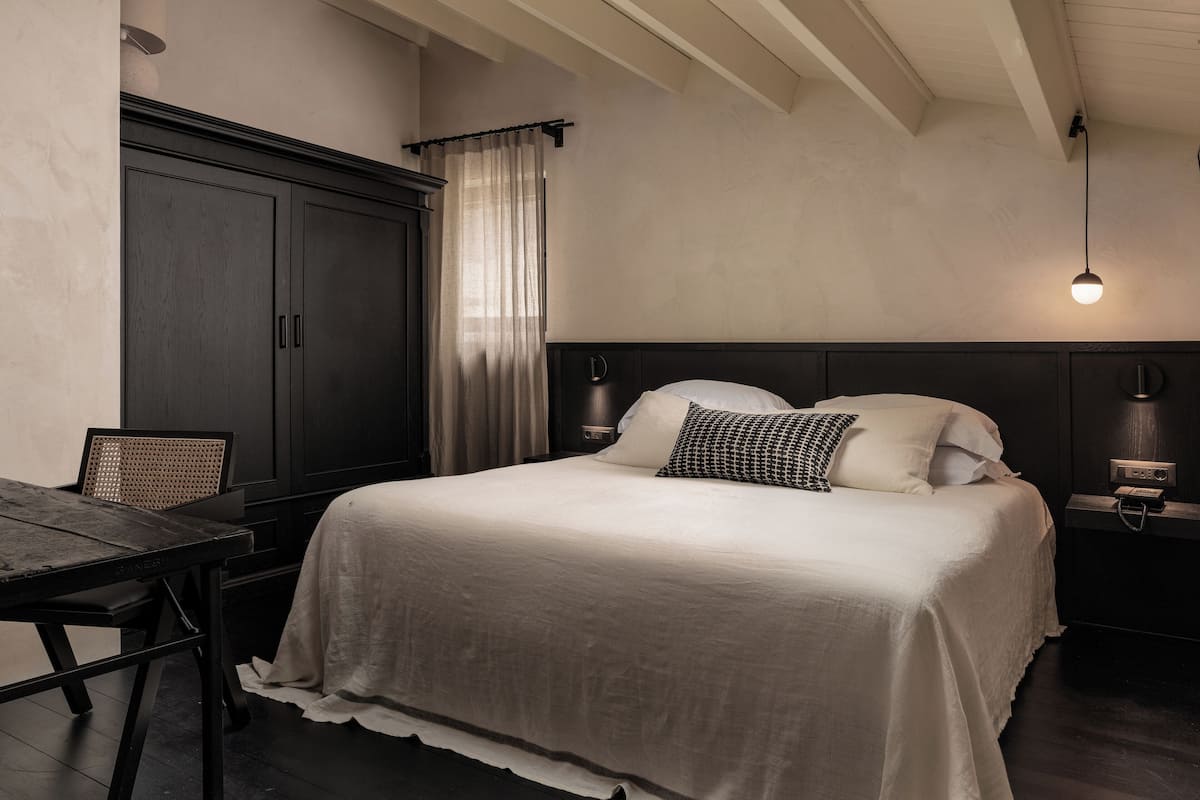 Un dormitorio con una cama grande, un armario de madera oscura, un escritorio y una silla.