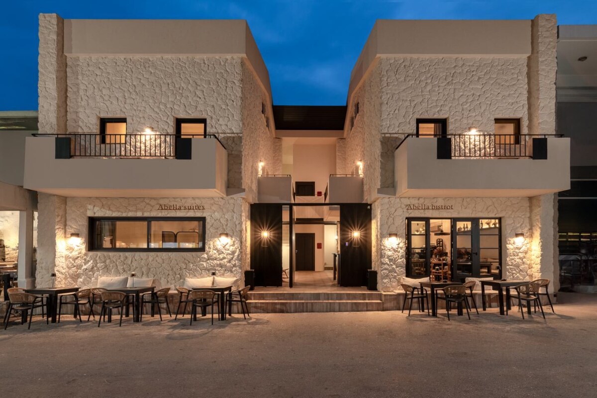 A modern building with a stone facade, two balconies, and outdoor seating areas.