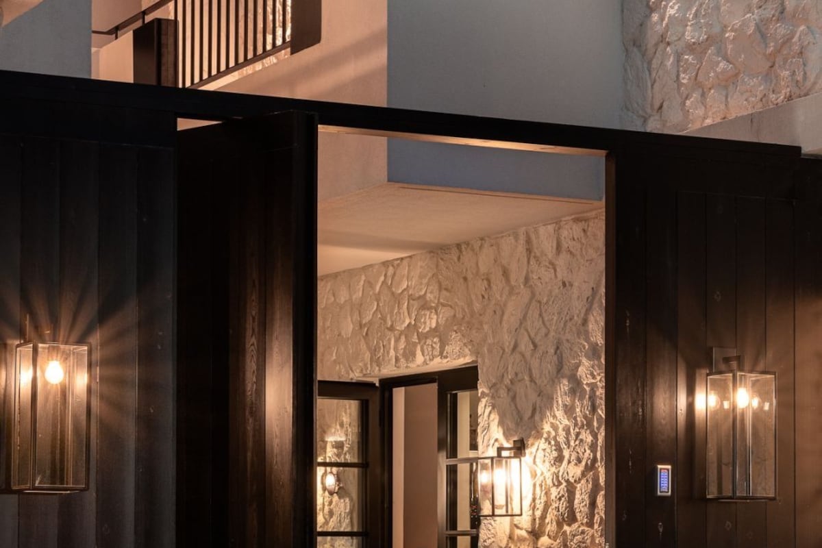 A modern interior with a stone wall, wooden flooring, and a bar area with stools.