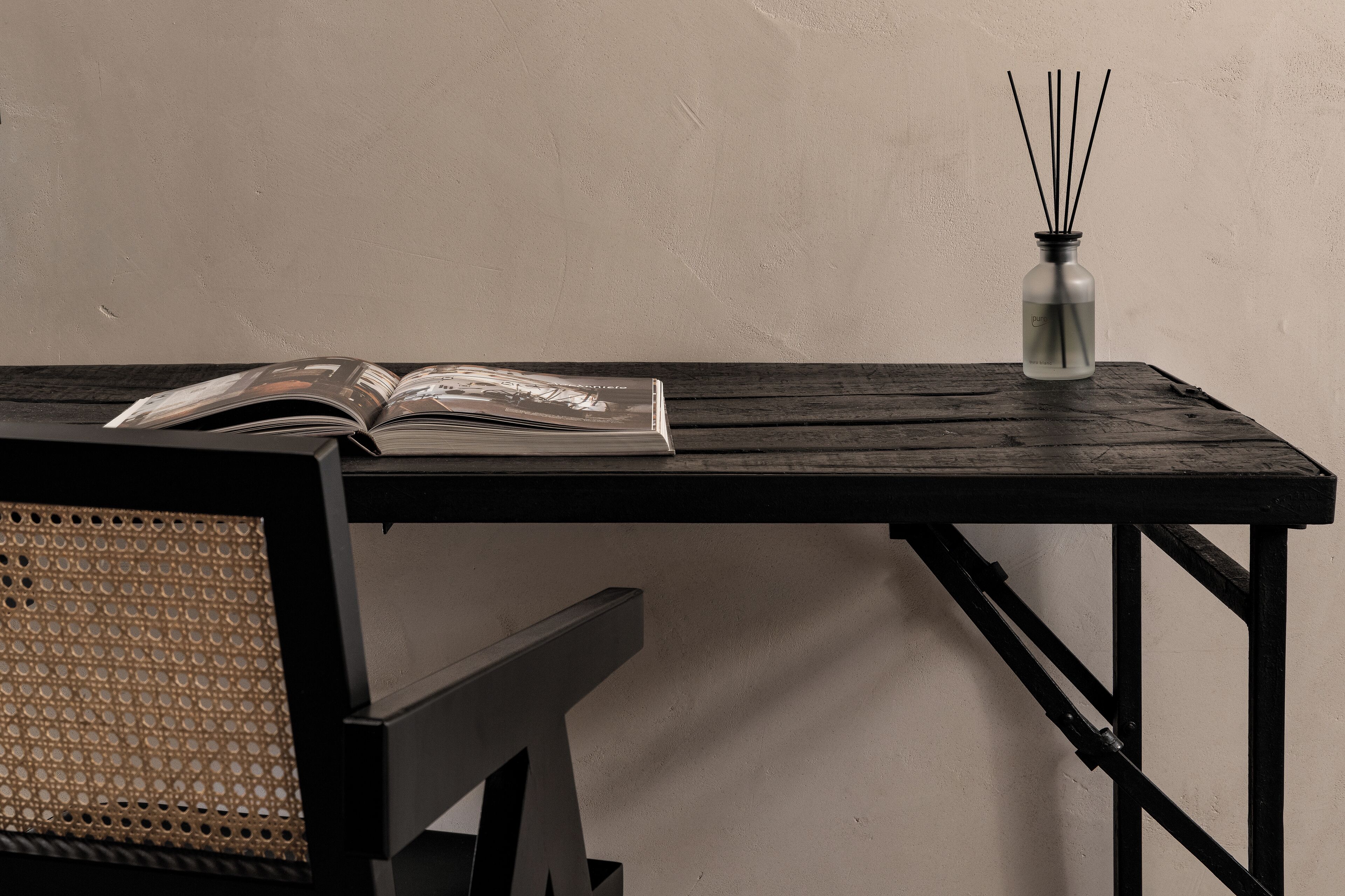 Ein Holztisch mit einem Buch und einem Reed-Diffuser.