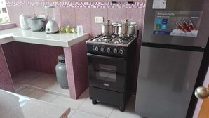 A kitchen with a gas stove, oven, refrigerator, and a blender on the counter.