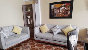 A living room with two grey sofas, a patterned floor, a bookshelf, and a framed picture on the wall.