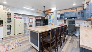 Una cocina con una isla central, sillas de madera, un ventilador de techo y armarios.