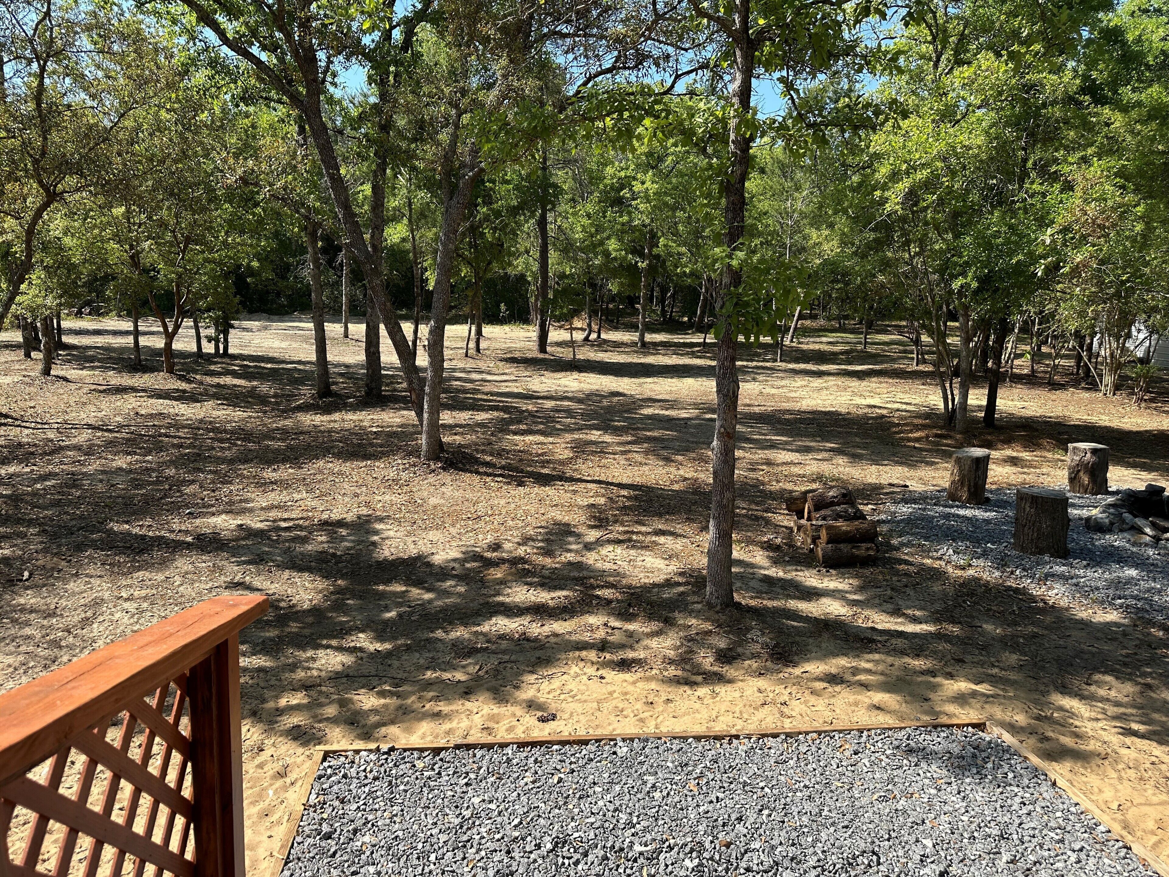 A campground with trees, gravel paths, and wooden benches.