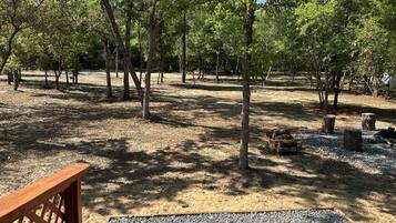 A campground with trees, gravel paths, and wooden benches.