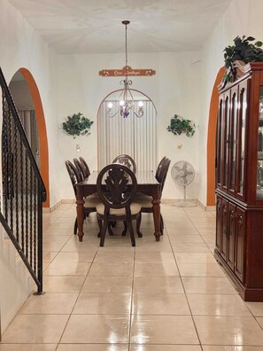 Comedor con candelabro, un aparador de madera y un ventilador.