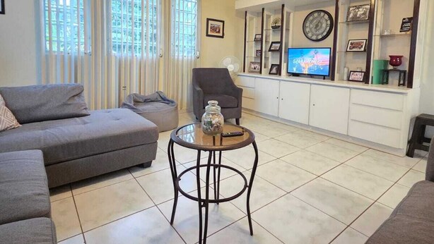 A living room with a sofa, a coffee table, a TV, and a ceiling fan.