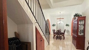 A spacious interior with a staircase, dining area, and a ceiling fan.