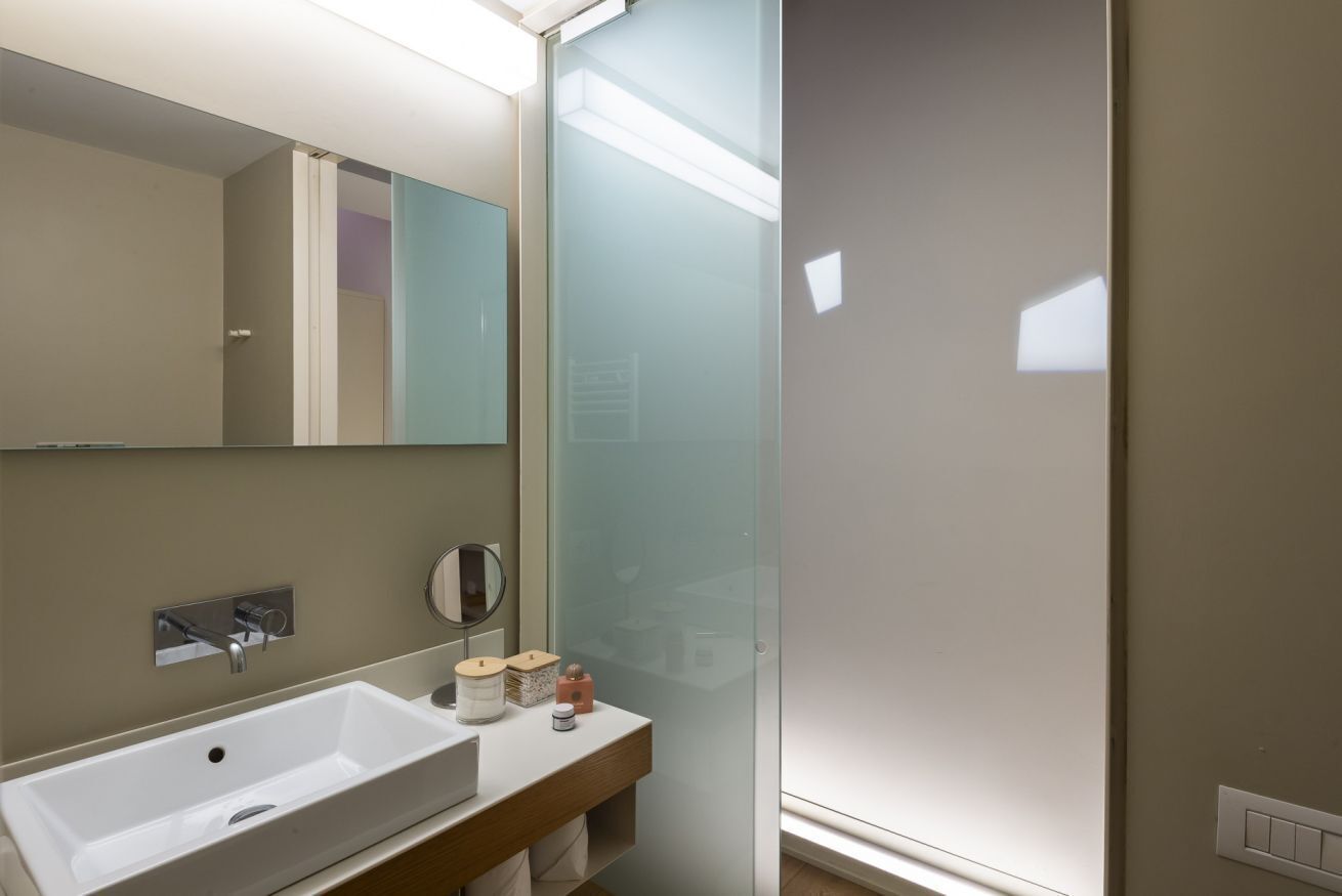 Une salle de bain moderne avec un grand lavabo blanc, un miroir et une cabine de douche en verre.