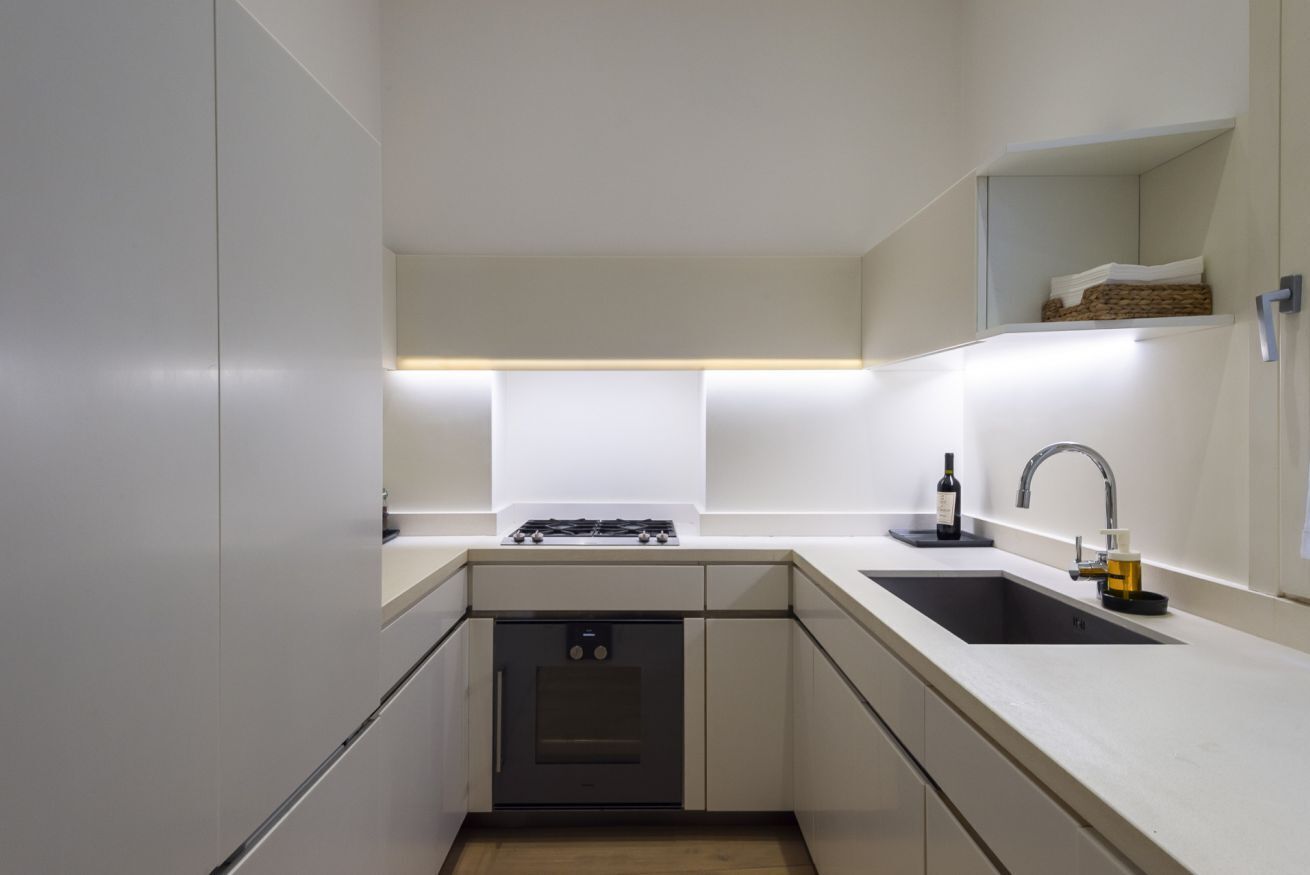 A modern kitchen with a built-in oven, a gas stove, a sink, and a countertop.