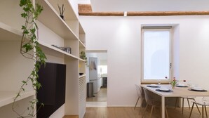 A modern kitchen with a built-in oven, a dining area with a table set for two, and a large window providing natural light.