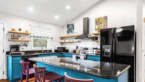 Una cocina moderna con una isla central, taburetes de bar y un refrigerador negro.