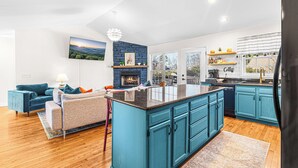 Una cocina moderna con armarios color turquesa, una isla central y una chimenea empotrada.