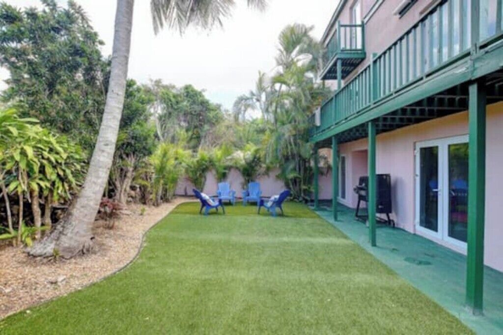 A hotel with a covered outdoor area, a lawn, and two lounge chairs.
