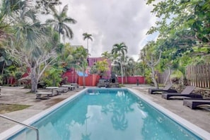 Uma piscina com espreguiçadeiras e palmeiras.