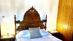 A bedroom with a wooden headboard, a bed with white bedding, two bedside tables with lamps, and a wooden wall panel.