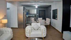 Una sala de estar moderna con un sofá, un sillón y un comedor con mesa y sillas.
