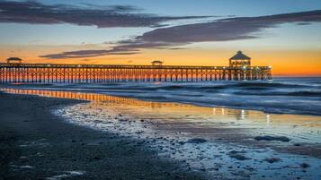 A pier extending into the ocean with a gazebo at the end, reflecting the sunset.