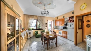 A spacious kitchen with a dining area, featuring a chandelier, wooden cabinets, and a tiled floor. - La Finestra Sul Mare (Ischia)