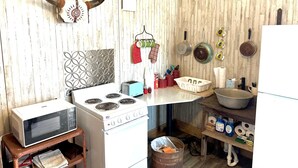 Una cocina con estufa, microondas y diversos utensilios.