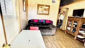 Un espacio habitable compacto con una mesa de comedor, un sofá, un ventilador de techo y un televisor.