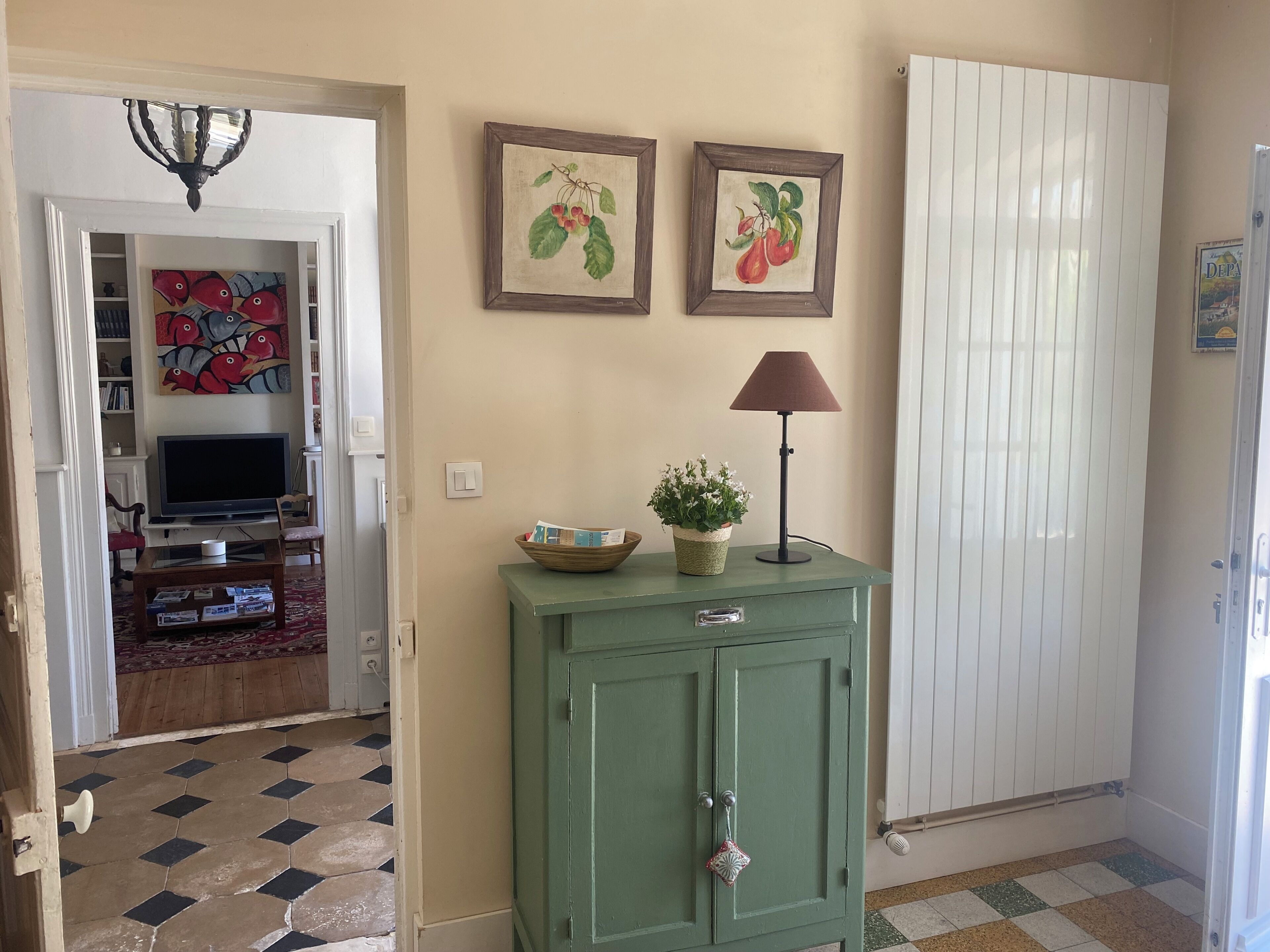 A living room with a television, a green cabinet, and two framed pictures on the wall.