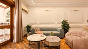 Moderni olohuone, jossa on harmaa sohva, kaksi pyöreää sohvapöytää ja suuri beige nojatuoli.