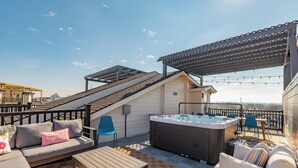 Une terrasse sur le toit avec un jacuzzi, des sièges d’extérieur et une pergola.