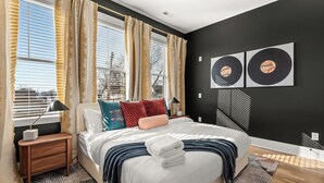 Une chambre à coucher moderne, dotée d’un grand lit, de tables de chevet et offrant une vue sur l’extérieur grâce à de grandes fenêtres.