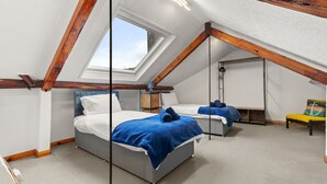 A bedroom with two beds, a skylight, and a sloped ceiling.
