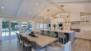 A spacious kitchen with a central island, white cabinetry, and a large dining area with chairs.