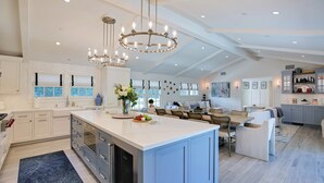 A spacious kitchen with a large island, white cabinetry, and a chandelier.