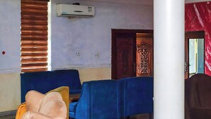 A room with a white pillar, a blue sofa, a brown leather chair, and a table with a blue tablecloth. - Nafelis Hotel Enugu (Enugu)