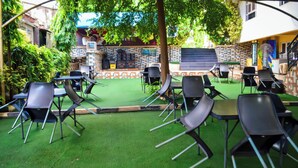 An outdoor seating area with tables and chairs, surrounded by a brick wall and greenery. - Nafelis Hotel Enugu (Enugu)
