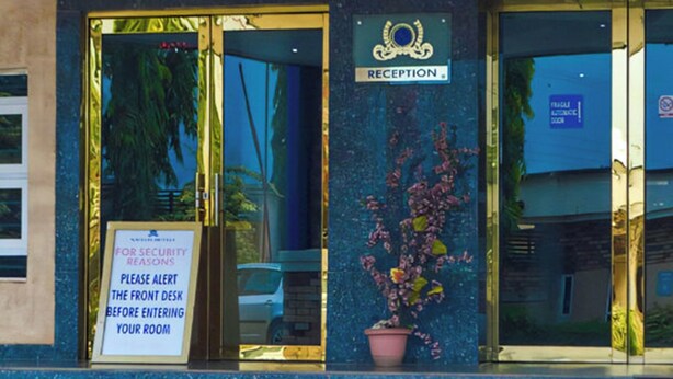 A reception area with a sign indicating 'RECEPTION' and a security notice advising to alert the front desk before entering. - Nafelis Hotel Enugu (Enugu)