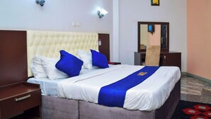 A hotel room with a large bed, a wooden nightstand, a dresser, and a mirror. - Nafelis Hotel Enugu (Enugu)