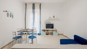 Ein modernes Wohnzimmer mit Essbereich, einem Flachbildfernseher und einem blauen Sofa.